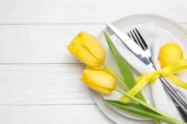 Paskalya kutlaması. Lale çiçekleri ve beyaz ahşap arka planda boyanmış yumurta ile şölen masası, üst manzara. Metin için boşluk