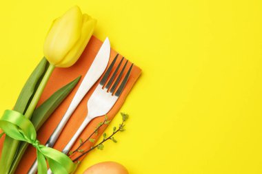 Paskalya kutlaması. Çiçekli masa dekoru ve sarı arka planda boyanmış yumurta, düz yatak. Metin için boşluk