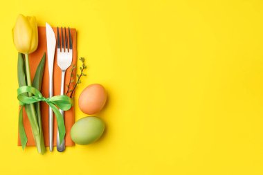 Paskalya kutlaması. Çiçekli masa dekoru ve sarı arka planda boyanmış yumurtalar, düz yatak. Metin için boşluk