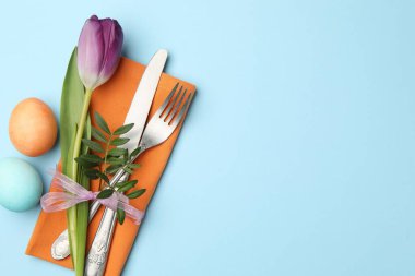 Paskalya kutlaması. Çiçekli masa dekoru ve açık mavi arka planda boyanmış yumurtalar. Metin için boşluk