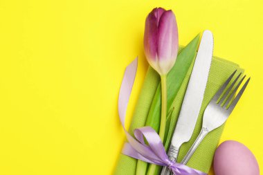 Paskalya kutlaması. Çiçekli masa dekoru ve sarı arka planda boyanmış yumurta, düz yatak. Metin için boşluk