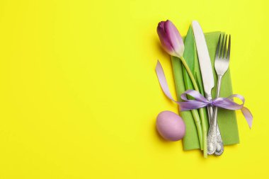 Paskalya kutlaması. Çiçekli masa dekoru ve sarı arka planda boyanmış yumurta, düz yatak. Metin için boşluk
