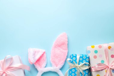 Mutlu Paskalyalar. Şirin tavşan kulakları ve açık mavi arka planda hediye kutuları, düz yatış. Metin için boşluk