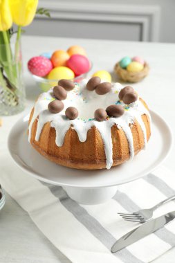 Lezzetli Paskalya pastası, boyanmış yumurtalar ve sarı laleler kapalı masa üzerinde, yakın plan.