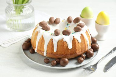 Çikolatalı lezzetli Paskalya pastası ve beyaz masaya boyanmış yumurtalar, yakın plan.