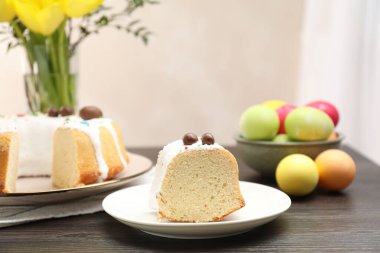 Paskalya pastasını kes, duvardaki ahşap masa üzerinde yumurta ve laleleri boya, yakın plan.