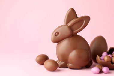 Çikolatalı Paskalya tavşanı ve pembe arka planda şekerli yumurtalar, yakın plan. Metin için boşluk