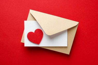 Sevgililer Günün kutlu olsun. Tebrik kartı ve kırmızı arka planda dekoratif kalp ile zarf, üst görünüm