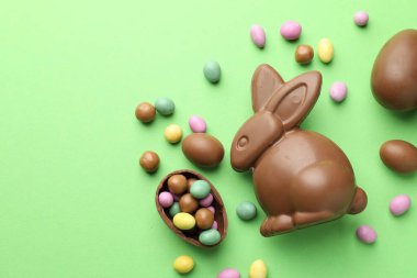 Çikolatalı Paskalya tavşanı ve açık yeşil arka planda yumurtalar. Metin için boşluk