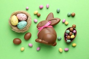 Çikolatalı Paskalya tavşanı ve açık yeşil arka planda yumurtalar.