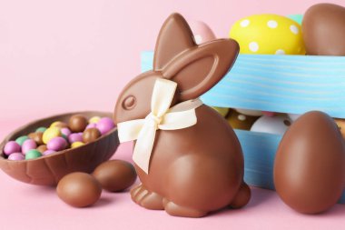 Çikolatalı Paskalya tavşanı ve pembe arka planda yumurtalar, yakın plan.