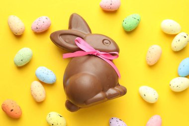 Çikolatalı Paskalya tavşanı ve sarı arka planda yumurtalar.