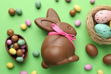 Çikolatalı Paskalya tavşanı ve açık yeşil arka planda yumurtalar.