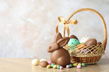 Çikolatalı Paskalya tavşanı ve hasır sepetteki yumurtalar açık gri arka planda, yakın plan. Metin için boşluk