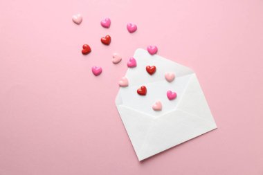 Tebrik kartı ve pembe arka planda dekoratif kalplerle dolu bir zarf. Sevgililer günün kutlu olsun.