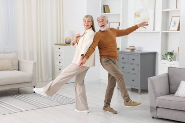 Mutlu yaşlı çift evde dans ediyor.