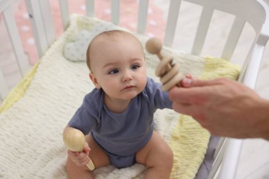 Babası evdeki beşiğinde sevimli küçük bebeğiyle oynuyor, yakın plan.