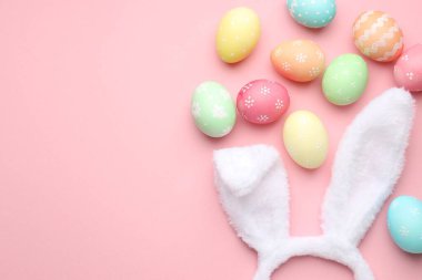 Mutlu Paskalyalar. Tavşan kulaklı şirin saç bandı ve pembe arka planda yumurta boyası, düz yatak. Metin için boşluk