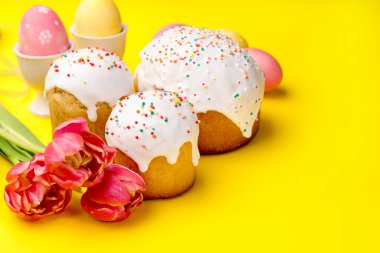 Lezzetli Paskalya pastaları, yumurta ve laleler sarı arka planda, yakın plan.