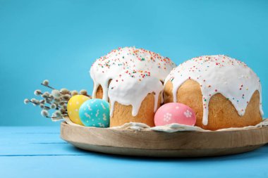 Lezzetli Paskalya pastaları, yumurtalar ve söğütler mavi ahşap masada.