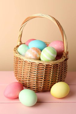 Güzel Paskalya yumurtaları pembe ahşap masanın üzerinde bej arka planda
