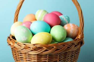 Açık mavi arkaplanda sepetteki güzel Paskalya yumurtaları, yakın plan.