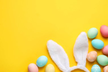 Mutlu Paskalyalar. Tatlı tavşan kulakları ve sarı arka planda boyanmış yumurtalar. Metin için boşluk