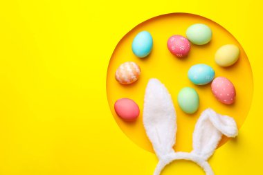 Mutlu Paskalyalar. Şirin tavşan kulakları ve sarı arka planda deliğe boyanmış yumurtalar. Metin için boşluk