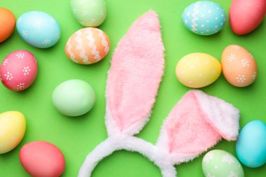 Mutlu Paskalyalar. Şirin tavşan kulakları ve yeşil arka planda boyanmış yumurtalar.