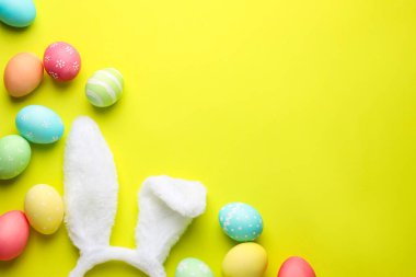 Mutlu Paskalyalar. Tatlı tavşan kulakları ve sarı arka planda boyanmış yumurtalar. Metin için boşluk