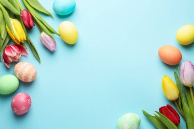 Boyanmış Paskalya yumurtaları ve açık mavi arka planda güzel laleler. Metin için boşluk