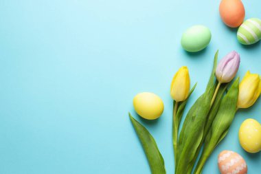 Boyanmış Paskalya yumurtaları ve açık mavi arka planda güzel laleler. Metin için boşluk