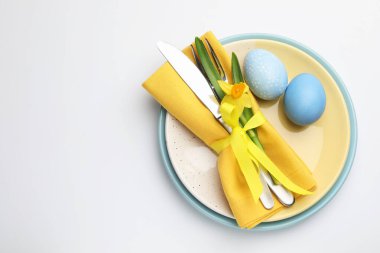 Paskalya kutlaması. Nergis çiçekli şenlik masası ve beyaz arka planda boyanmış yumurtalar, üst manzara. Metin için boşluk