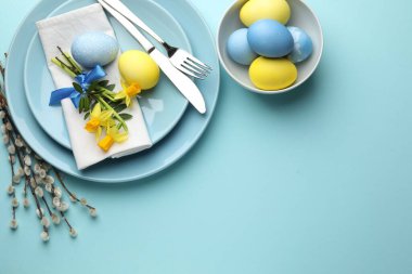 Paskalya kutlaması. Üzerinde nergis çiçekleri, boyalı yumurtalar ve açık mavi arka planda söğüt dalları olan şenlik masası düzlüğü. Metin için boşluk