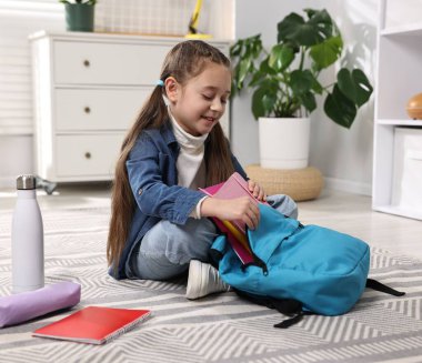 Okul için sırt çantasını toplayan bir kız.