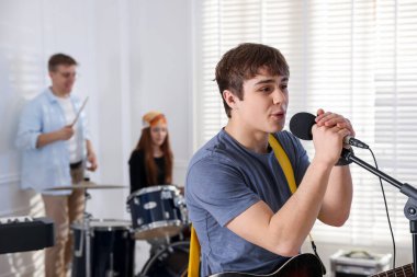 Genç müzik grubu içeride performanslarını prova ediyor.