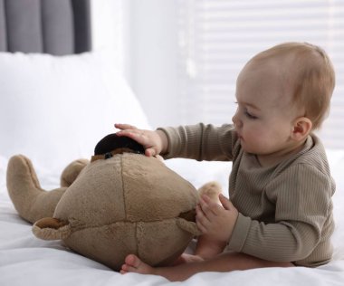 Evde yatağında oyuncak ayıyla sevimli bir bebek.