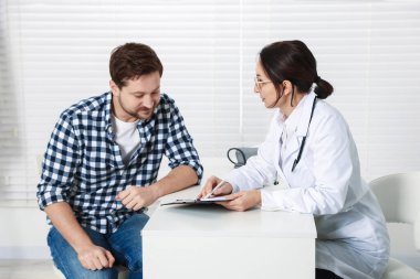 Klinikteki beyaz masada pano danışmanı olan bir doktor.