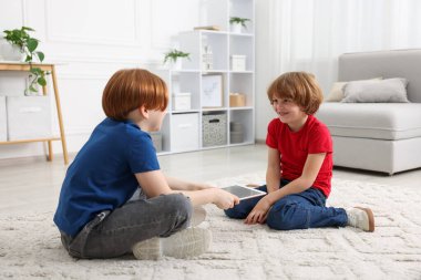 Evde tabletleri olan sevimli kardeşler.