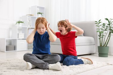 İki kardeş evde yerde oynaşıyor.