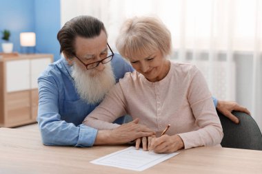 Ahşap masada son arzuları ve vasiyetnameleri imzalayan yaşlı çift.