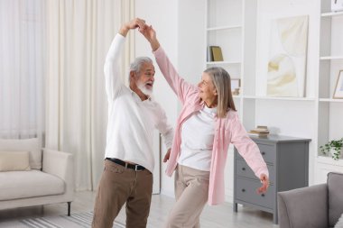 Mutlu yaşlı çift evde dans ediyor.