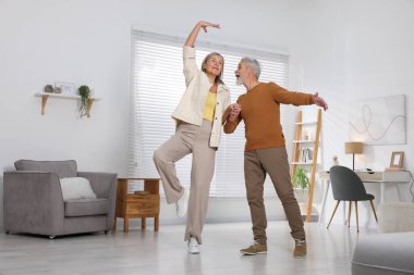 Mutlu yaşlı çift evde dans ediyor.