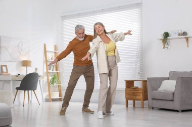 Mutlu yaşlı çift evde dans ediyor.