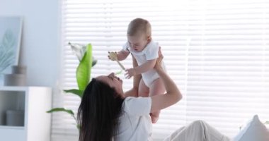 Anne, bebeğiyle evde yatakta oynuyor.