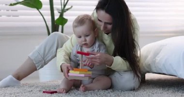 Anne ve bebeği evde oyuncak piramitlerle oynuyorlar.