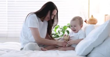 Anne, tatlı bebeğiyle evde yatakta oynuyor.