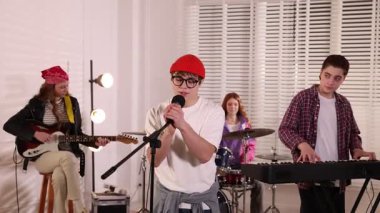 Genç müzik grubu içeride performanslarını prova ediyor.