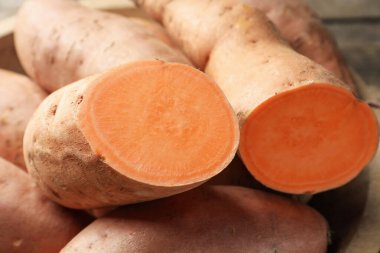 Raw sweet potatoes on table, closeup. Whole and cut