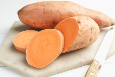 Çiğ patates ve bıçak beyaz ahşap masada, yakın plan.